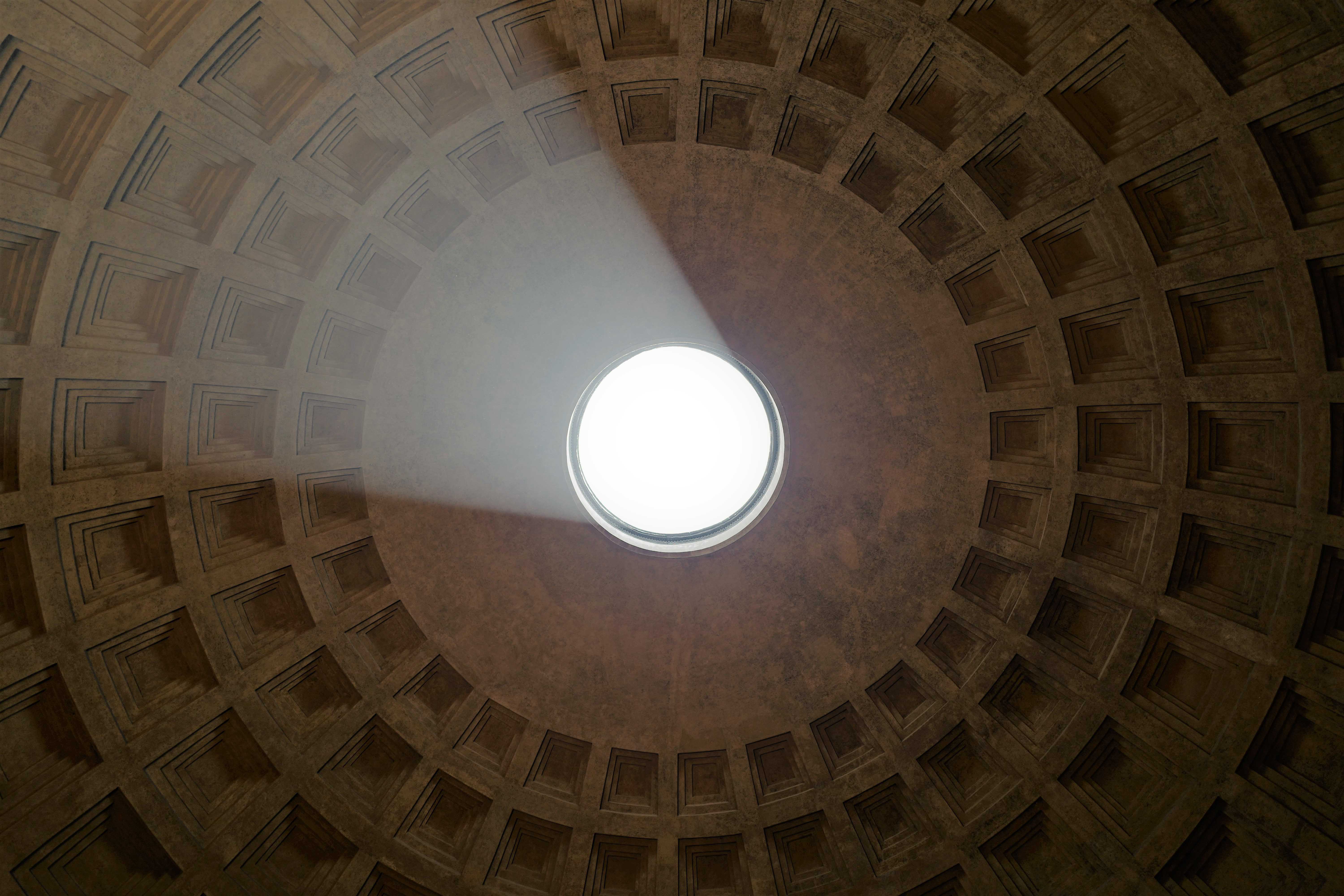 Das Bild zeigt eine Aufnahme von innen einer großen, runden Kuppel. Die Kuppel hat ein zentrales Opaion oder Loch an der Spitze, durch das Tageslicht einfällt und den Innenraum beleuchtet. Ein Strahl des einfallenden Lichts ist sichtbar und beleuchtet einen Teil der inneren Oberfläche der Kuppel. Die innere Oberfläche der Kuppel ist mit regelmäßig angeordneten, rechteckigen Vertiefungen verziert. Die Farbpalette des Bildes besteht hauptsächlich aus warmen Erdtönen, die durch das natürliche Licht hervorgehoben werden. Das Pantheon in Rom wurde von unten fotografiert und ist als Wandbild erhältlich.